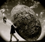 Image of business woman rolling a giant stone